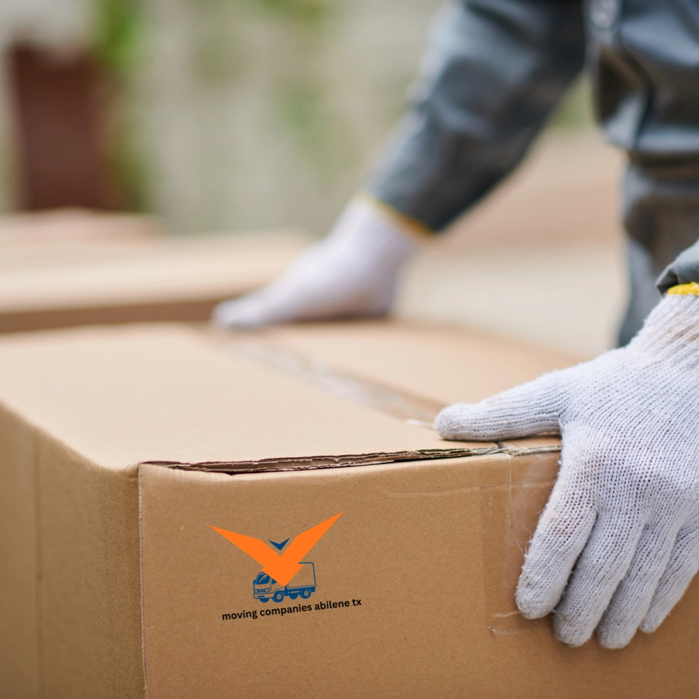 A professional mover wearing safety gloves carefully sealing a cardboard box, demonstrating the high standards of Abilene moving companies.